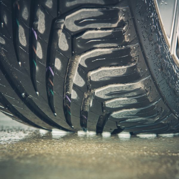 Brand New Vehicle Tire Tread Closeup Photo. Car Wheel on the Wet Pavement.